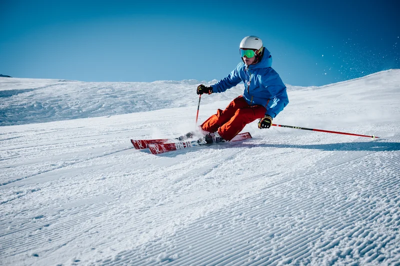 Skier carving dynamically on a pristine alpine slope under clear blue sky